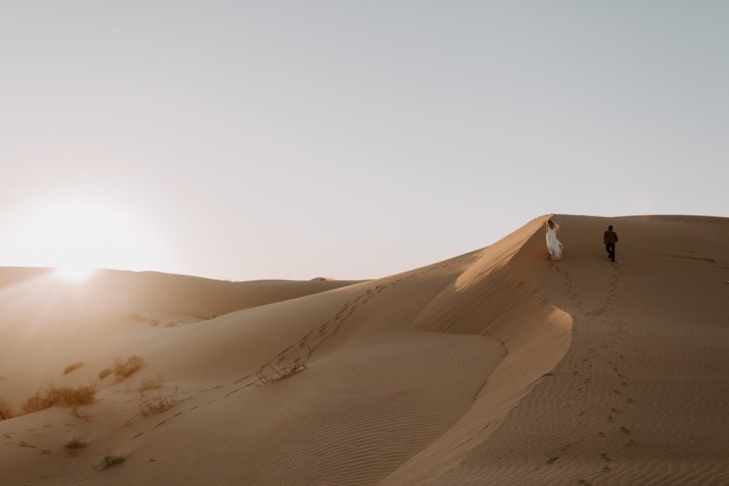 Couple climbing sand dunes in sunset Glamis Elopement