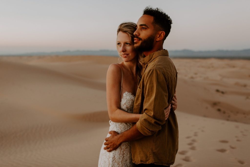 Couple climbing sand dunes in sunset Glamis Elopement