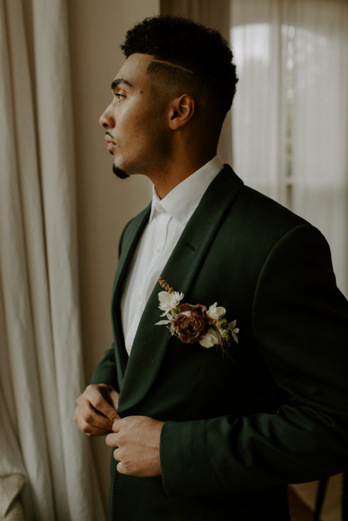 Emerald green suit on a groom in his airbnb in Madison Wisconsin getting ready before his elopement